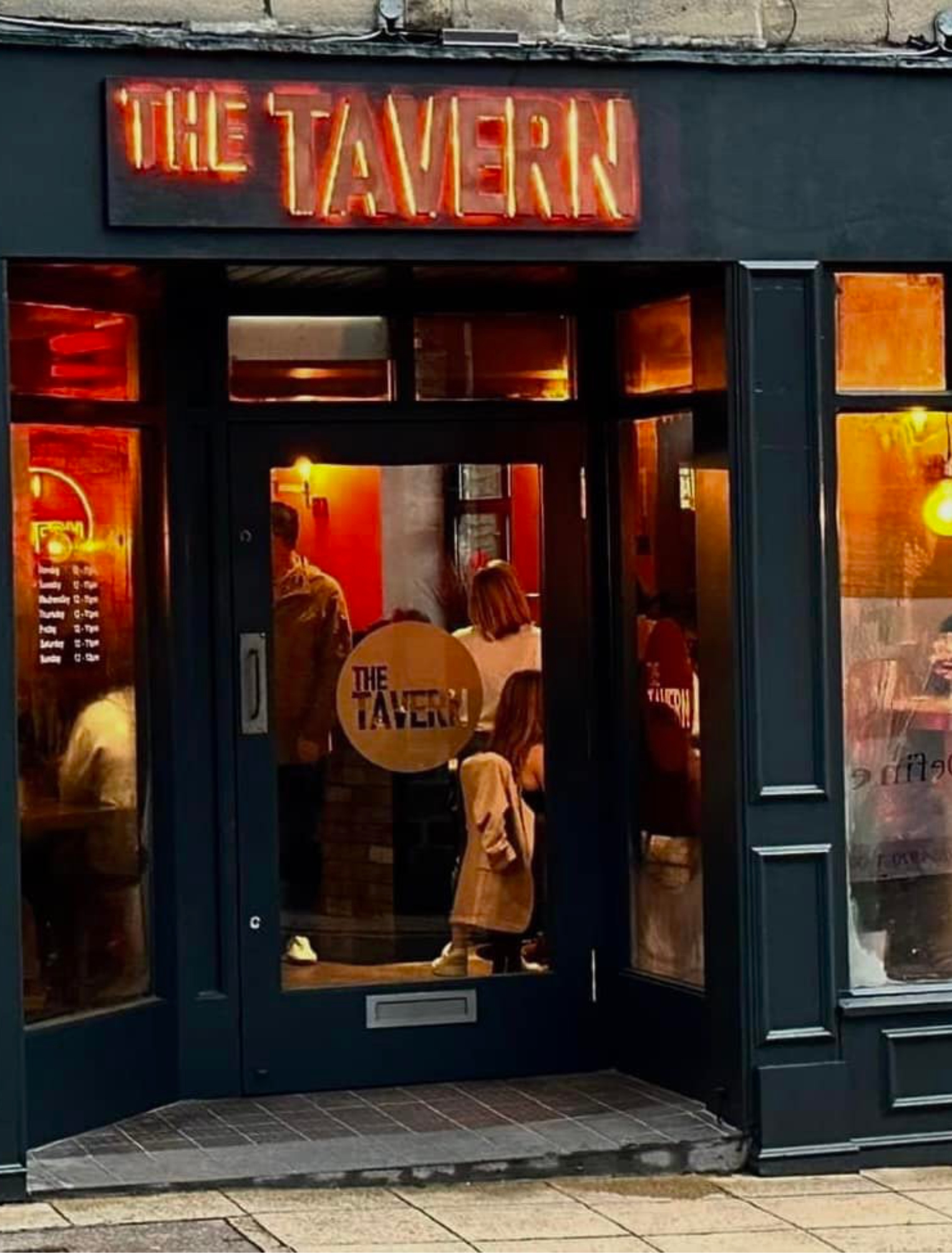The Tavern's dark frontage and glowing sign on Town Street